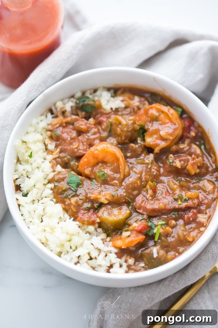 Healthy authentic seafood gumbo in a bowl with shrimp and okra over cauliflower rice in a white bowl with a spoon