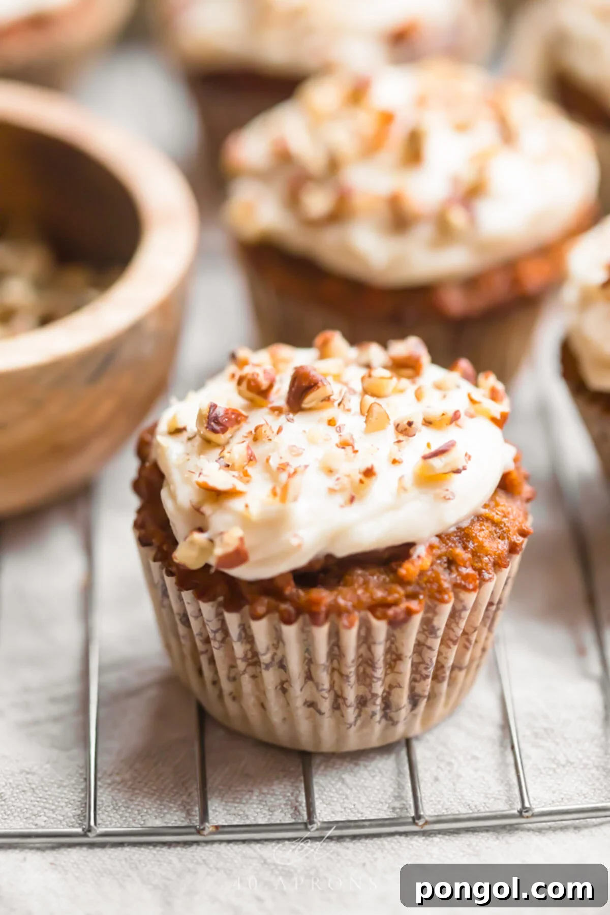 Delicious Paleo Carrot Cake Cupcakes Free From Gluten and Dairy 4 Paleo carrot cake cupcakes with cream cheese frosting on a wire cooling rack.