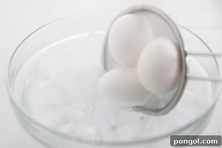 Strainer putting boiled eggs into a water bath.