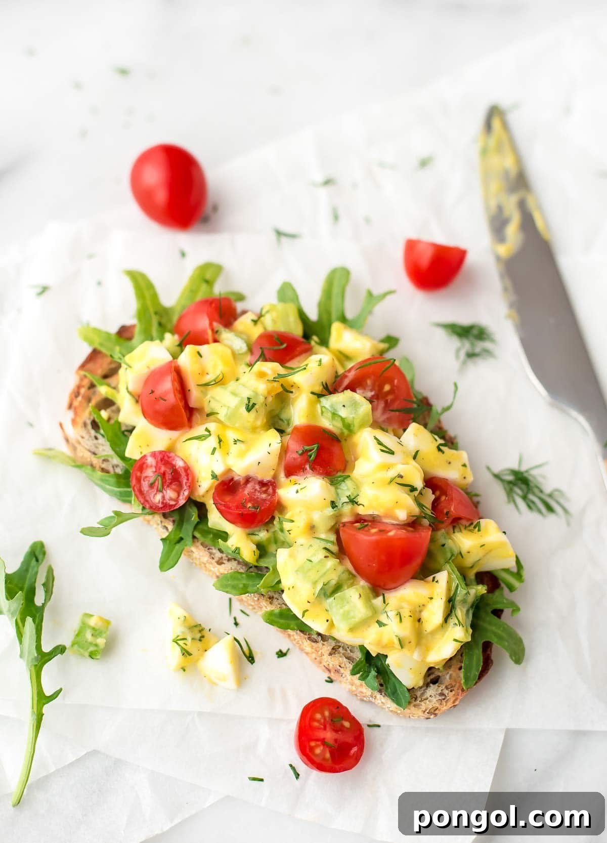 Overhead shot of healthy egg salad on a slice of sourdough bread with tomatoes