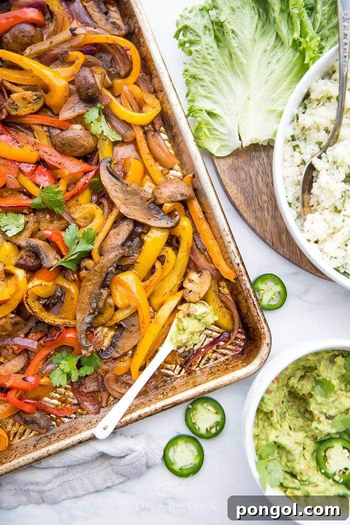 Overhead shot of vibrant Sheet Pan Vegetarian Fajitas served with a side of creamy cilantro lime cauliflower rice and a bowl of fresh guacamole.
