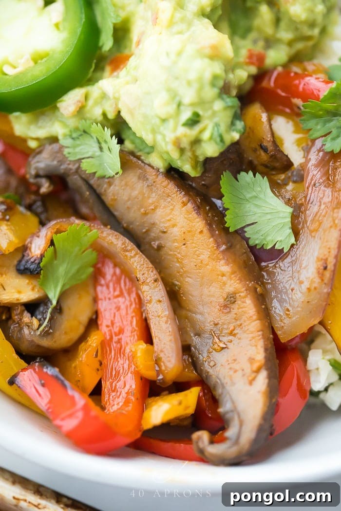 Close-up of perfectly roasted bell peppers, onions, and mushrooms on a sheet pan, ready to be served as vegetarian fajitas.