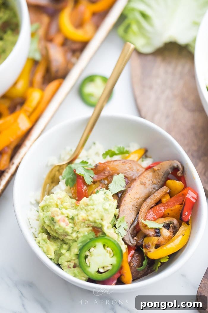 A vibrant vegetarian fajita burrito bowl, generously topped with creamy guacamole and fresh pico de gallo.