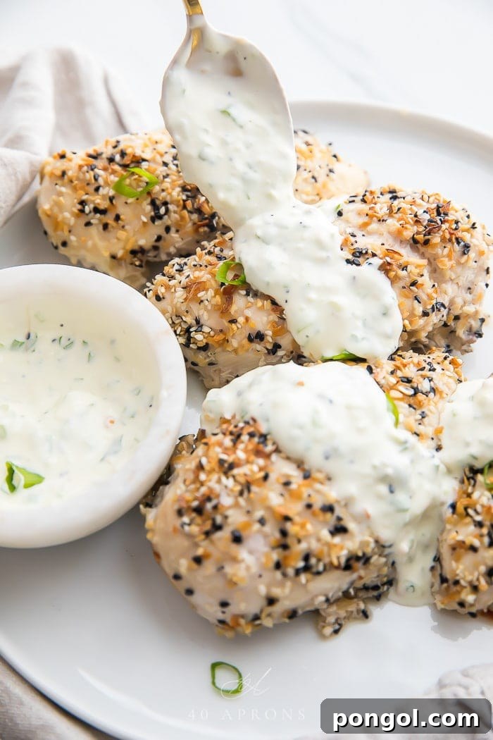 Everything Bagel seasoned chicken breasts with a spoon putting cream cheese sauce on