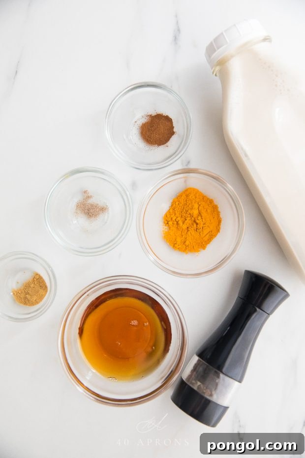 Ingredients for Iced Golden Milk: vivid turmeric powder, aromatic spices, and creamy plant milk, artfully arranged for a healthy and refreshing vegan beverage.