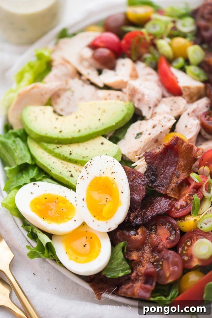 Close-up shot of perfectly cooked soft boiled eggs and crispy bacon on a classic chicken cobb salad, highlighting the texture and freshness of the ingredients.