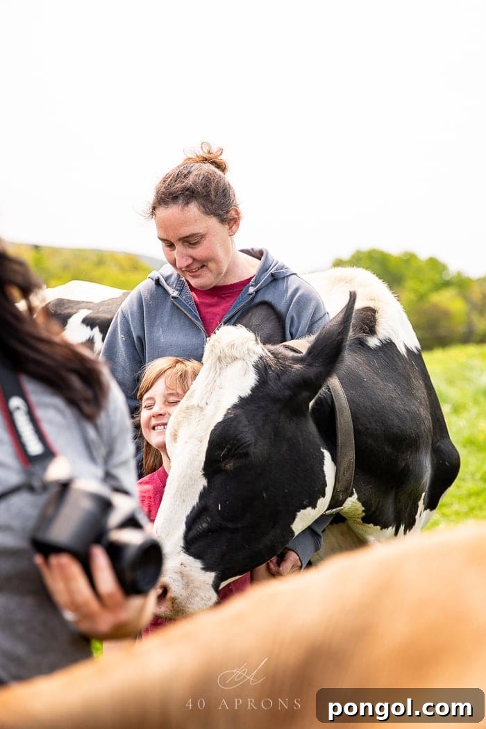 A farmer and her daughter affectionately hugging a dairy cow at Wonder Why Farm in Vermont, illustrating a deep connection to their animals.