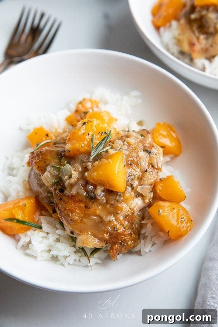 Apricot chicken served over white rice in a white bowl, garnished with fresh rosemary.