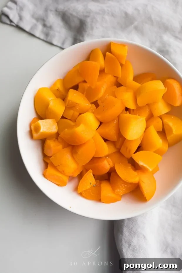 Close-up of evenly diced fresh apricots in a white bowl, ready for cooking.