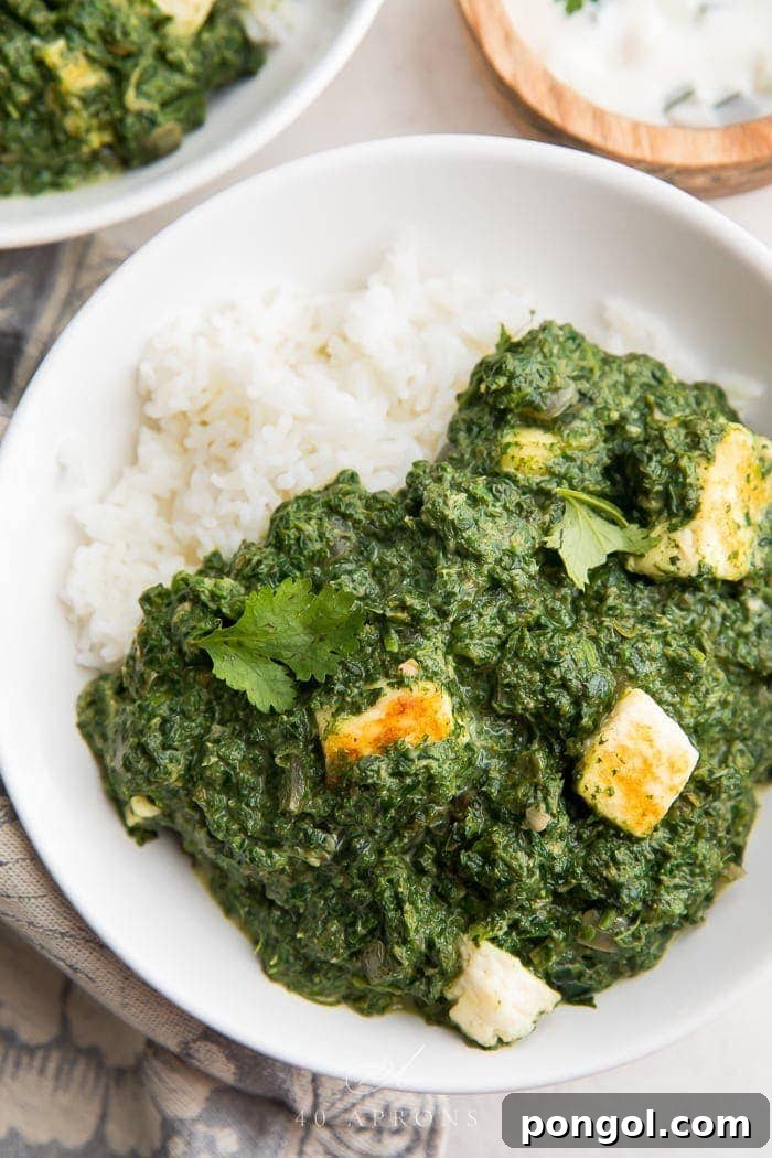Authentic Palak Paneer: Creamy Indian Spinach and Paneer Curry A bowl of palak paneer over rice, garnished with fresh cilantro, showcasing its rich green color and creamy texture.