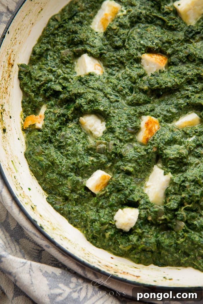 Creamy Palak Paneer in Skillet A vibrant green Palak Paneer simmering in a skillet, showcasing its creamy texture and the cubed paneer pieces within.