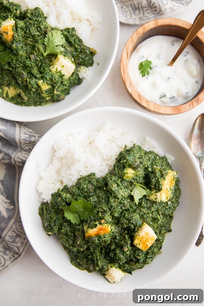 Palak Paneer with Rice and Raita Two bowls of Palak Paneer served over rice, with a side of raita and naan bread, ready to be enjoyed.