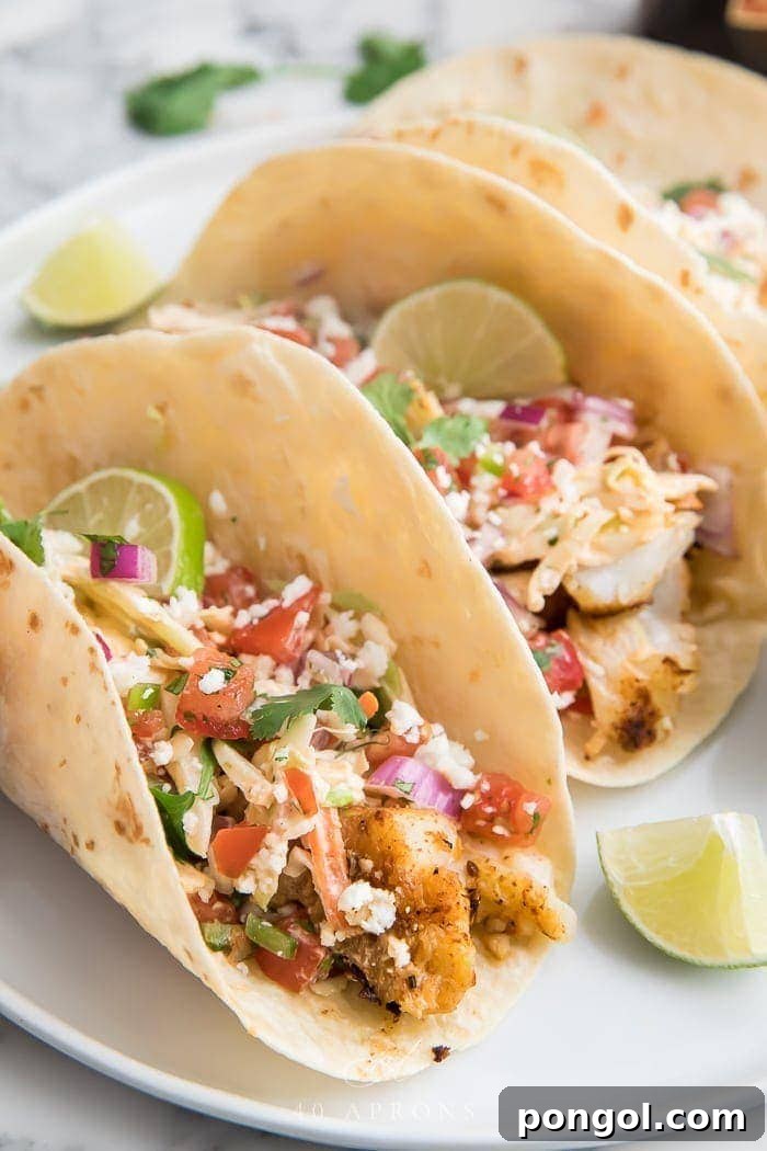 A close-up view of an easy fish taco, beautifully presented on a white plate, highlighting the perfectly cooked fish, vibrant slaw, and creamy chipotle sauce.