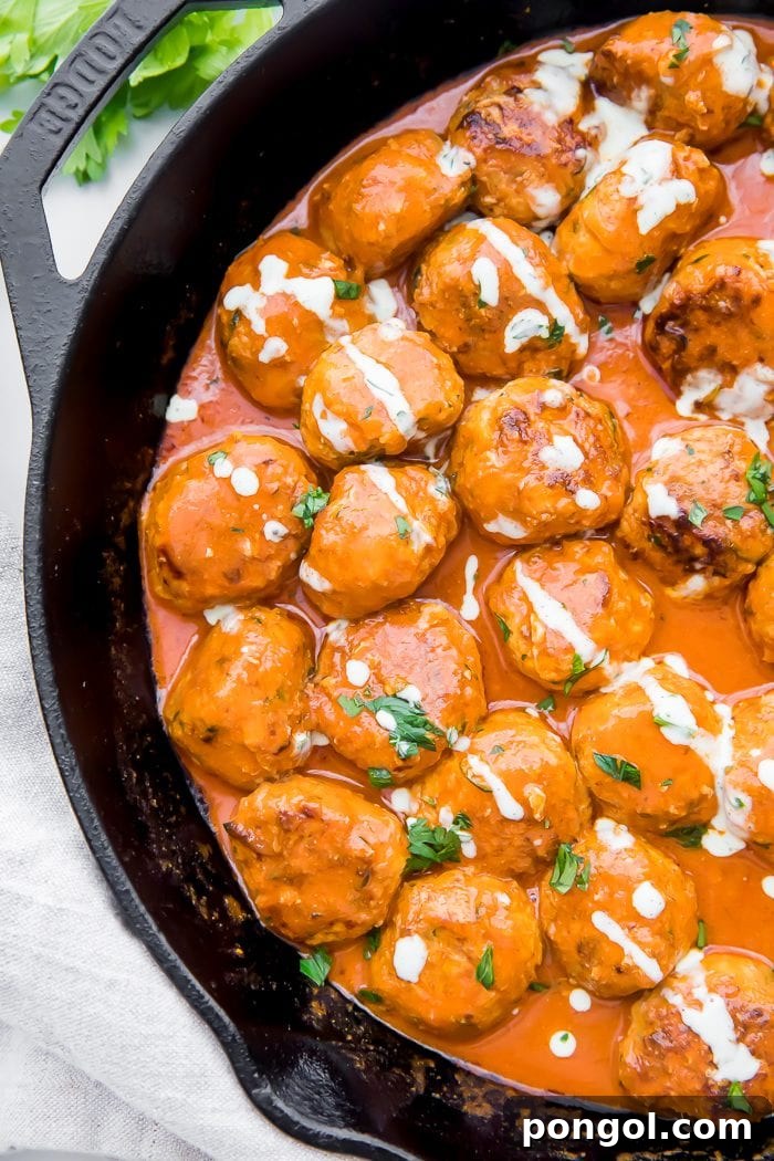 Tangy Buffalo Chicken Poppers 2 Top-down shot of tender buffalo chicken meatballs in a skillet, coated in creamy sauce