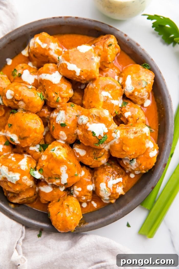 Tangy Buffalo Chicken Poppers 5 Buffalo Chicken Meatballs in a rustic bowl, garnished with fresh herbs and a drizzle of ranch