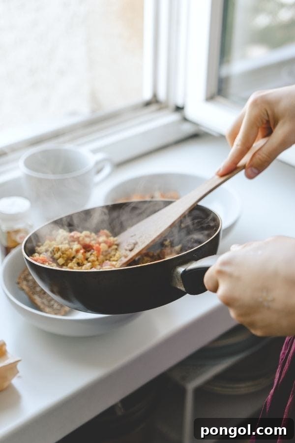 A close-up shot of colorful vegetables like bell peppers, onions, and broccoli being sauteed in a black pan.
