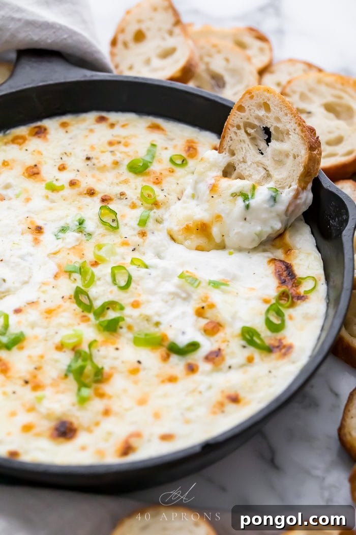 A piece of crostini being dipped into the creamy hot crab dip