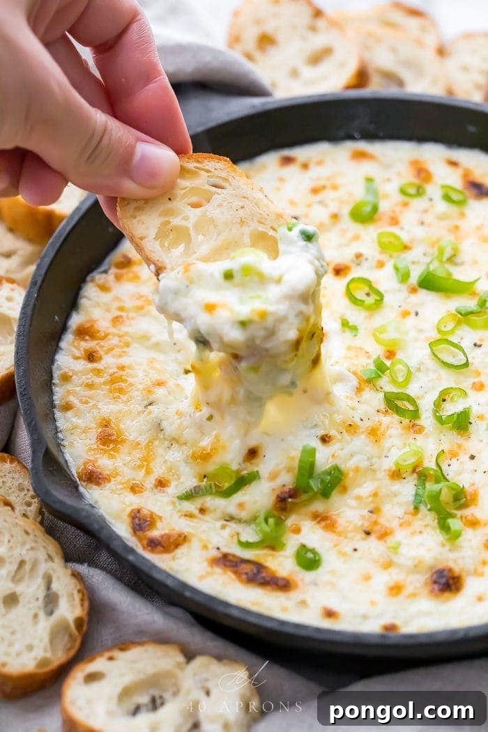 A close-up of a crostini being dipped into the freshly baked crab dip
