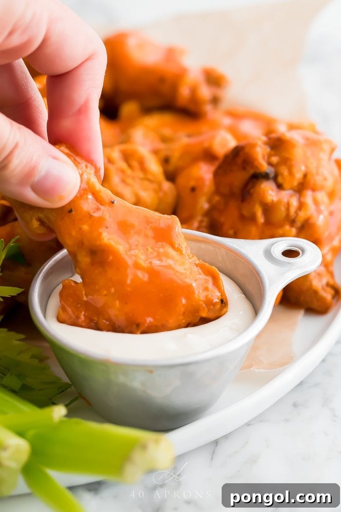 A chicken wing being dipped in sauce