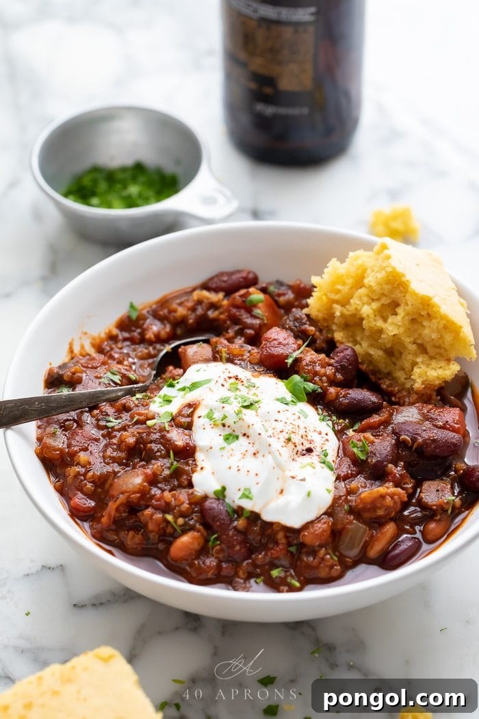 A beautifully presented bowl of vegan chili, topped with creamy avocado slices, vibrant cilantro, and a dollop of dairy-free sour cream, ready to be enjoyed.
