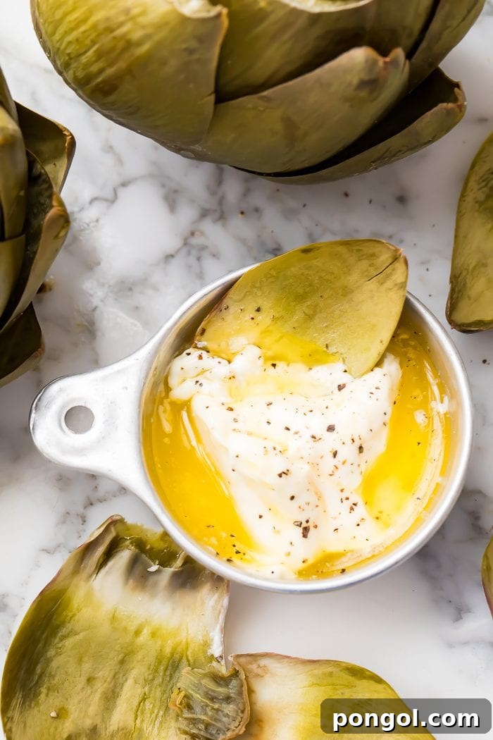 Close-up of an artichoke leaf being dipped in melted butter and mayonnaise sauce