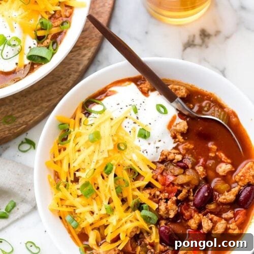 Turkey chili served in a white bowl with toppings
