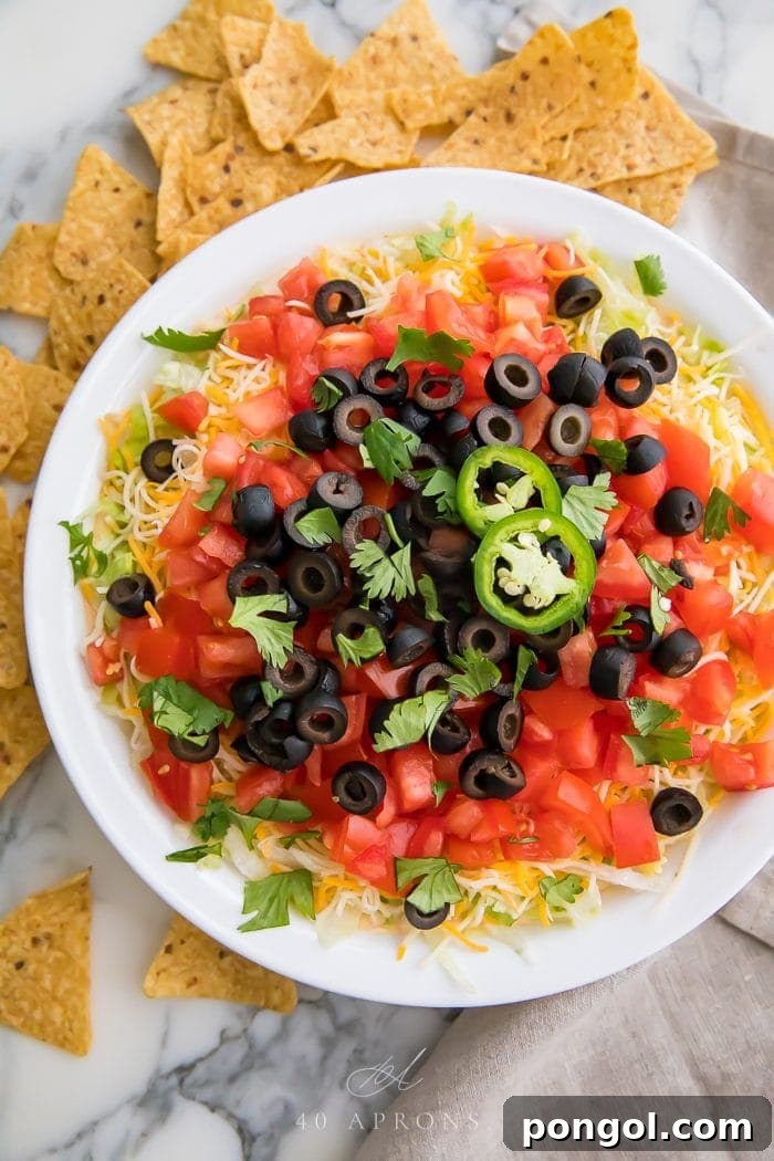 Taco dip in a white dish with tortilla chips around