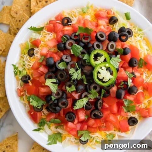 Taco dip in a white dish with tortilla chips around