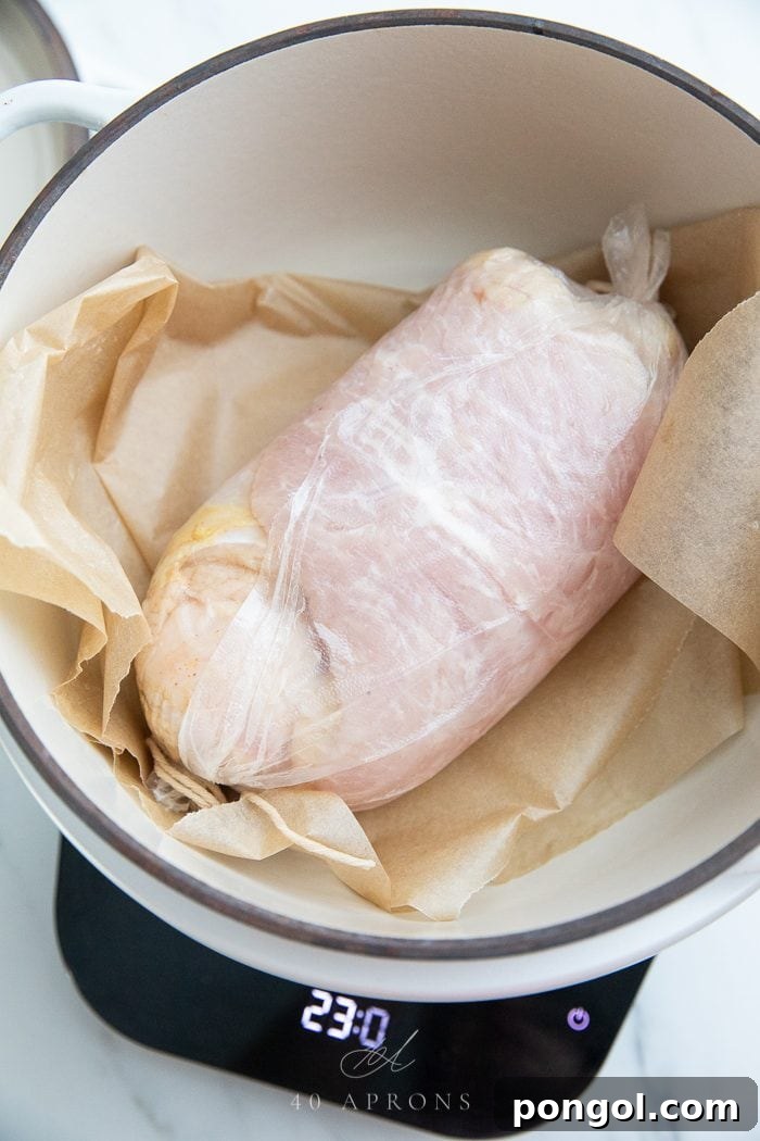A turkey breast wrapped and laid on parchment in a pot
