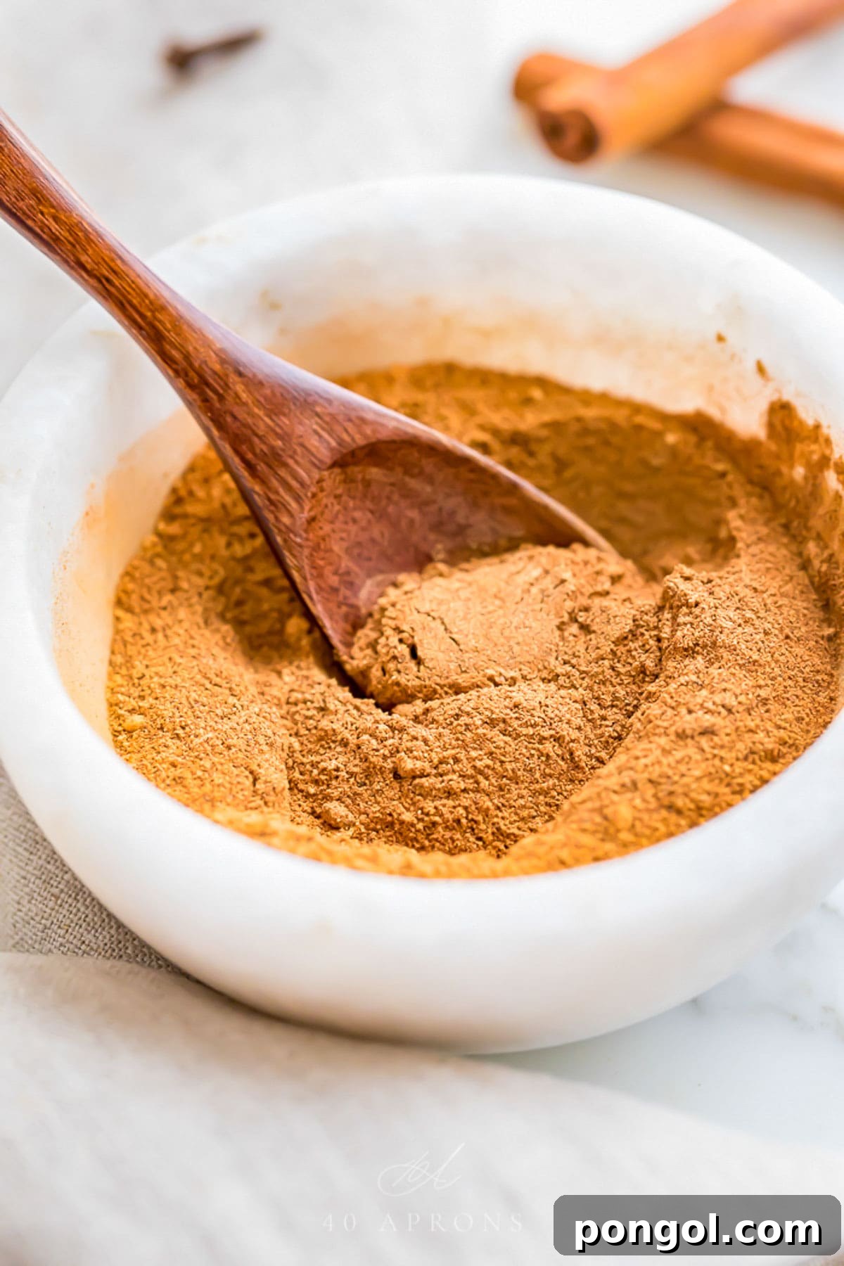 Homemade pumpkin pie spice blend in a small marble bowl with a small wooden spoon.