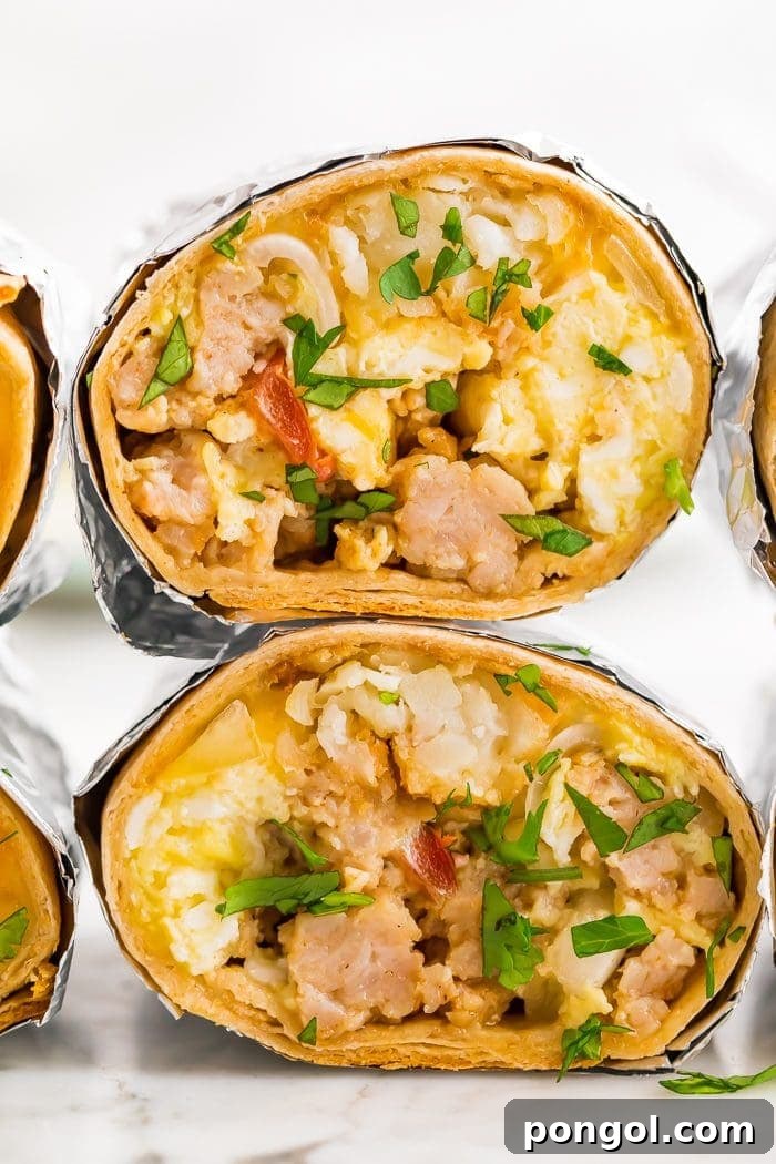 two freezer-friendly healthy whole wheat breakfast burritos with eggs, potatoes, sausage, bacon and cheese