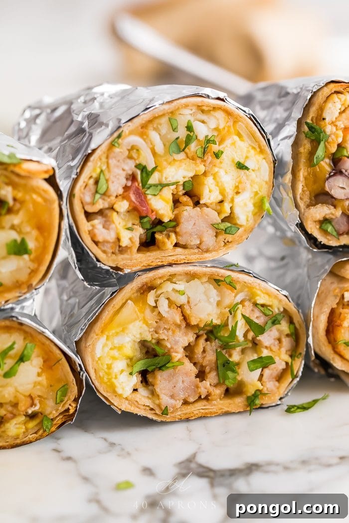 stacked healthy freezer breakfast burritos wrapped in aluminum foil