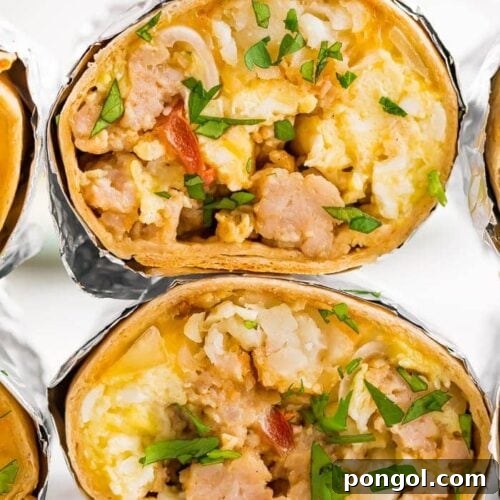 two freezer-friendly healthy whole wheat breakfast burritos with eggs, potatoes, sausage, bacon and cheese