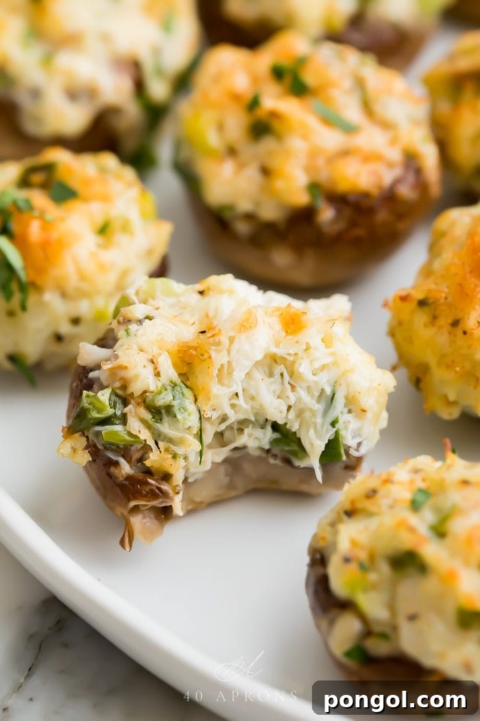 A close-up of a crab stuffed mushroom with a bite taken out of it, revealing the rich filling