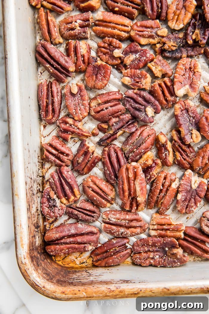 Roasted Butter Pecans 3 Raw pecan halves carefully spread out in a single, even layer on a parchment-lined sheet pan, prepared for baking.