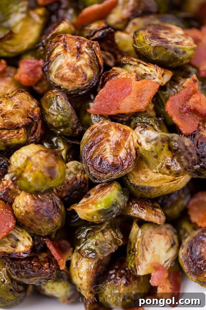 A close-up shot of perfectly roasted balsamic Brussels sprouts generously topped with crispy bacon bits, served in a rustic bowl.