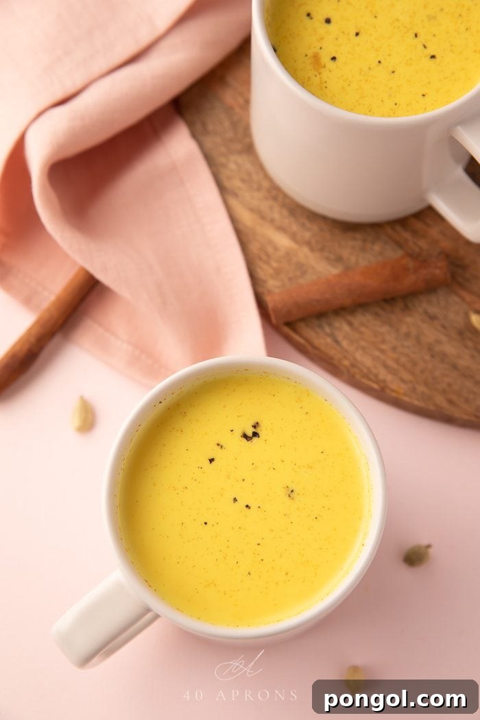 A white mug filled with golden milk, with a cinnamon stick resting on the rim and scattered star anise nearby, creating an inviting, spiced ambiance.