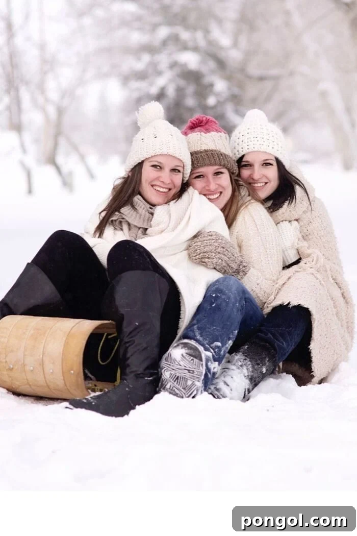 three women wearing cozy Scandi-style beanies and winter coats, laughing while riding on a sled, embodying joyful outdoor hygge activities
