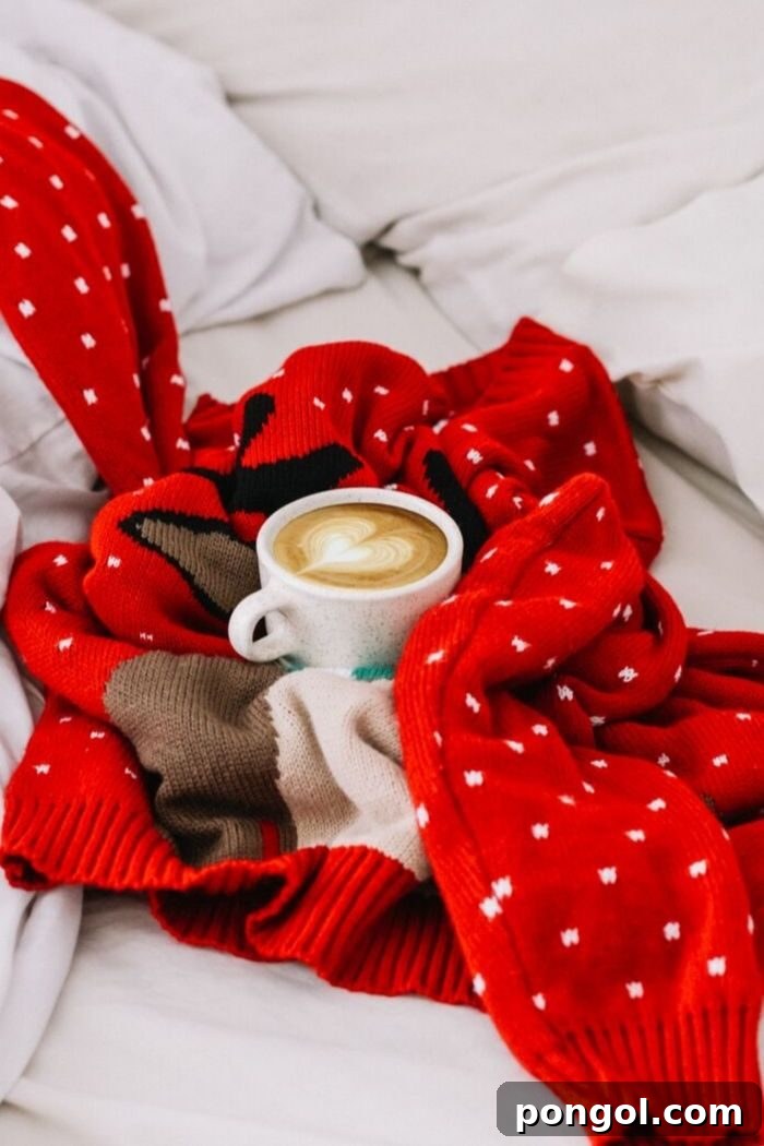 a mug of cappuccino thoughtfully nestled into a red Christmas sweater on a cozy bed, emphasizing warmth and comfort