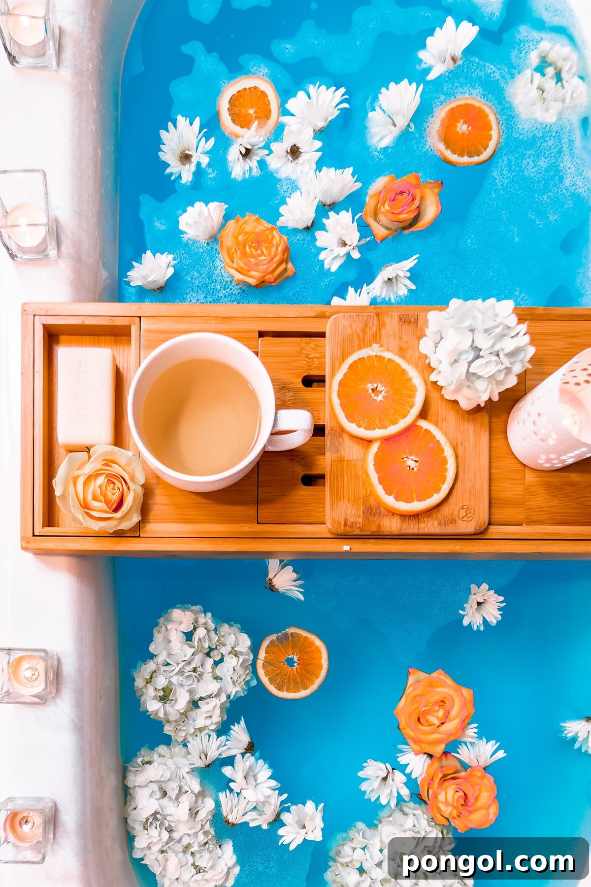 Overhead view of a luxurious bathtub filled with bright blue, inviting water and adorned with vibrant orange slices and delicate white flowers. A wooden tray conveniently spans the tub, holding a warm cup of coffee, creating an idyllic scene of relaxation and indulgence.