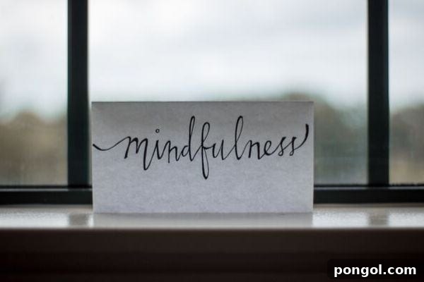 A small piece of paper with the word 'mindfulness' elegantly written on it, leaning against a sunlit window. The image evokes a sense of peace and introspection, highlighting the importance of presence in daily life.