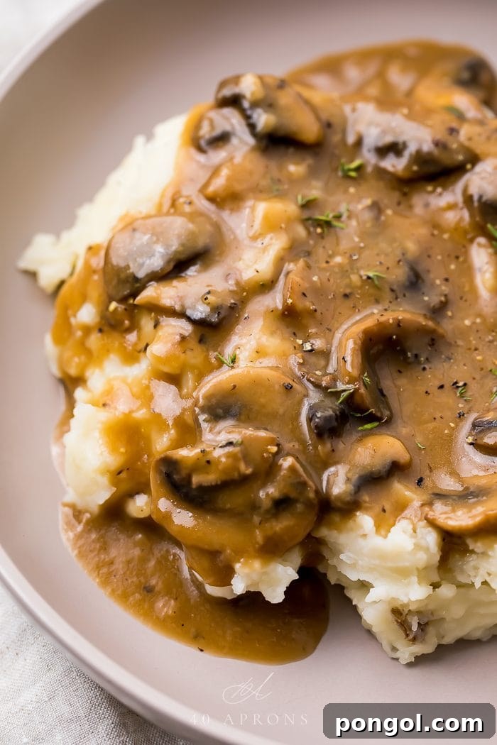 A bowl of creamy mashed potatoes generously topped with rich mushroom gravy, highlighting its perfect pairing for comfort food.