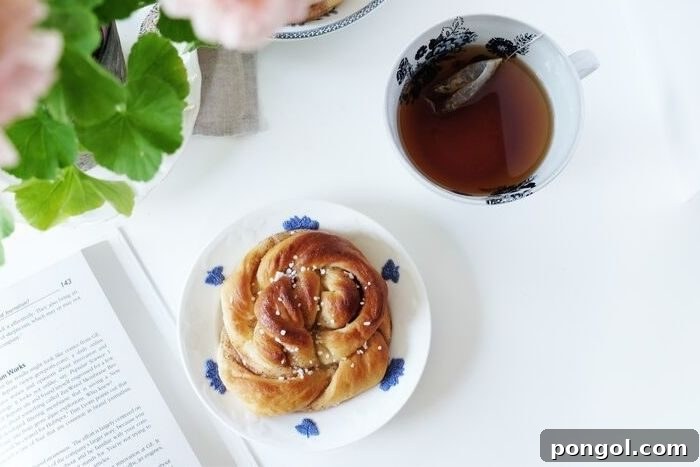 a cinnamon roll between a mug of tea and a book