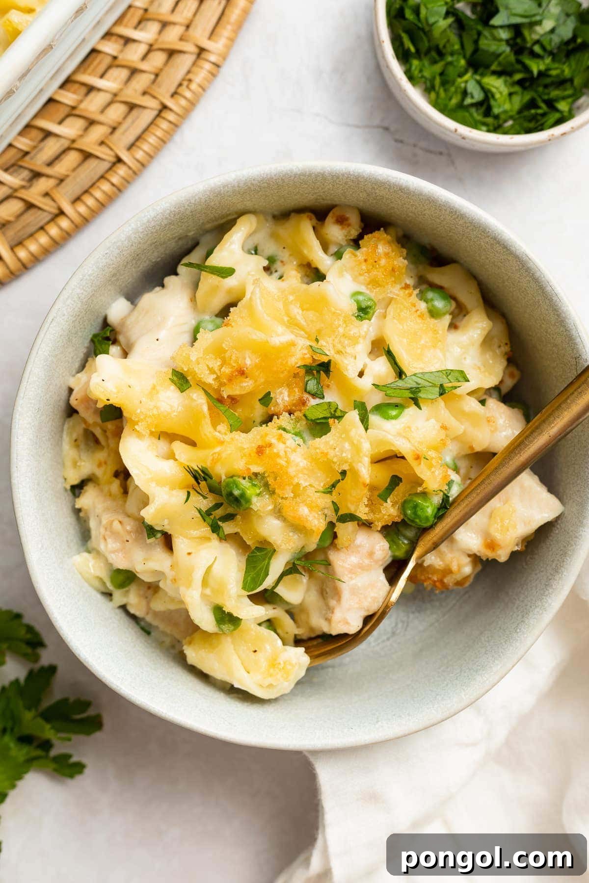 A bowl of creamy leftover turkey casserole, garnished with fresh parsley on the side, invitingly plated to highlight its comforting texture and rich ingredients.