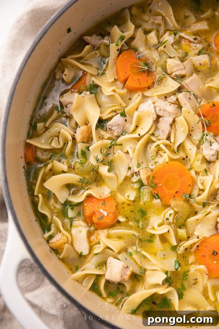 A large pot of Leftover Turkey Noodle Soup simmering on the stovetop, radiating warmth and comfort, filled with tender turkey pieces, noodles, and aromatic vegetables.