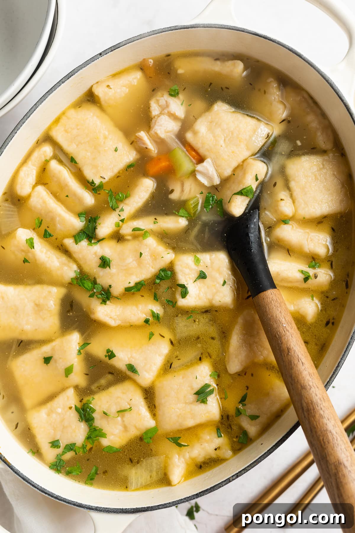 A Dutch oven brimming with homemade turkey and dumplings, highlighting the fluffy dumplings nestled amongst tender turkey in a rich, comforting broth.