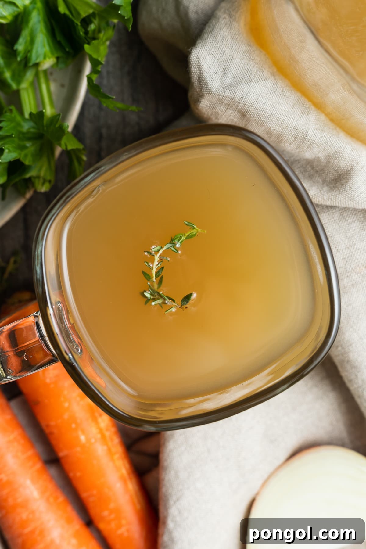 A warm mug of rich crockpot bone broth garnished with fresh thyme, presented invitingly to showcase its comforting and savory qualities.