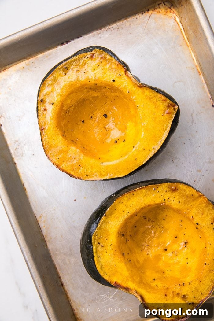 Two halves of roasted acorn squash on a plate, showcasing the vibrant orange flesh