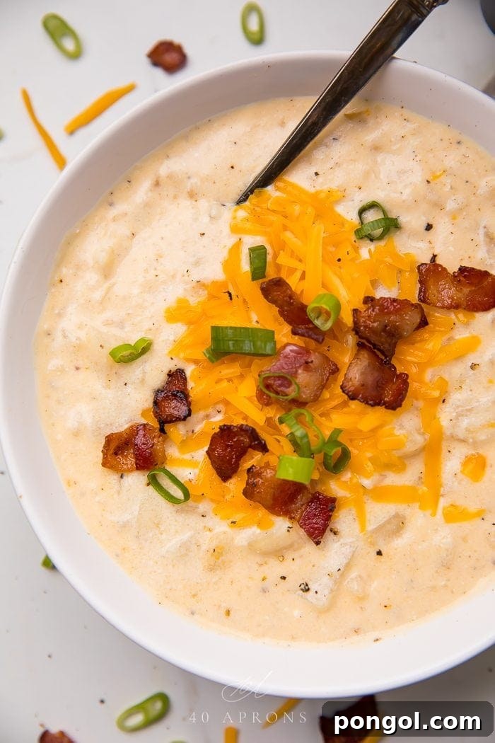 Creamy Crockpot Potato Soup, generously topped with crispy bacon bits and fresh chives, served in a rustic bowl.