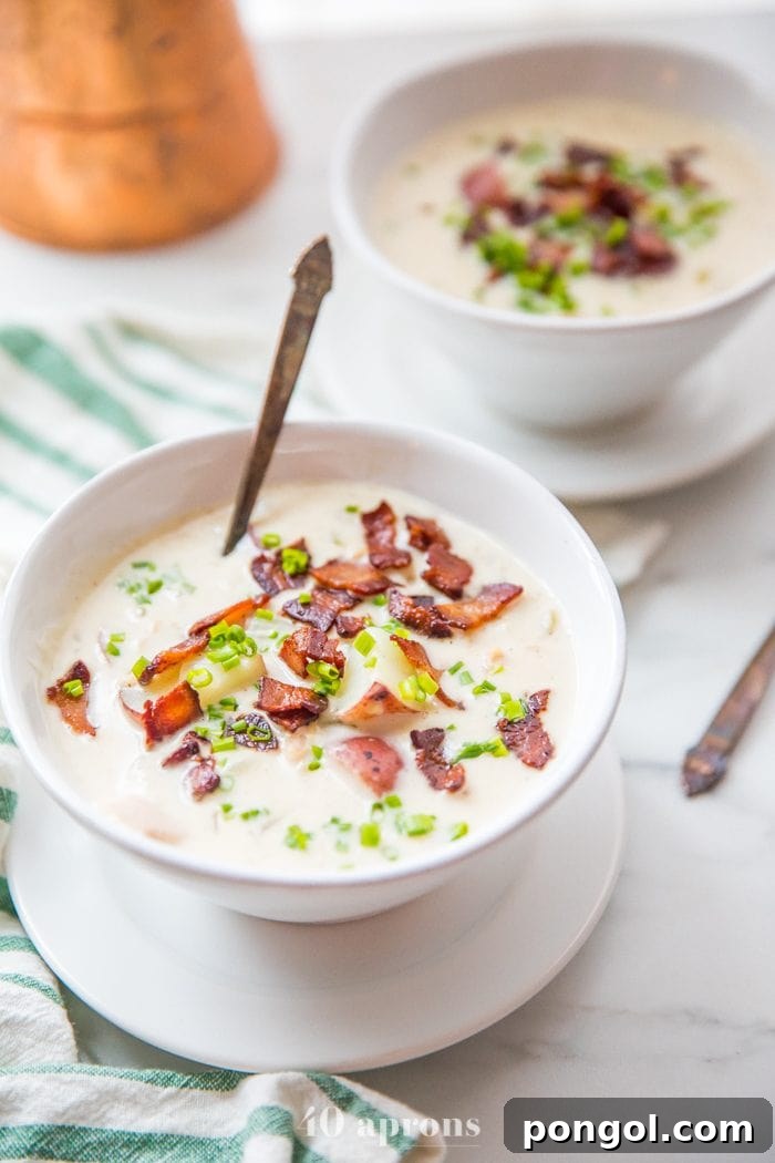 A hearty bowl of Healthy Creamy Clam Chowder, showcasing its rich, thick texture and generous portions of clams and potatoes.